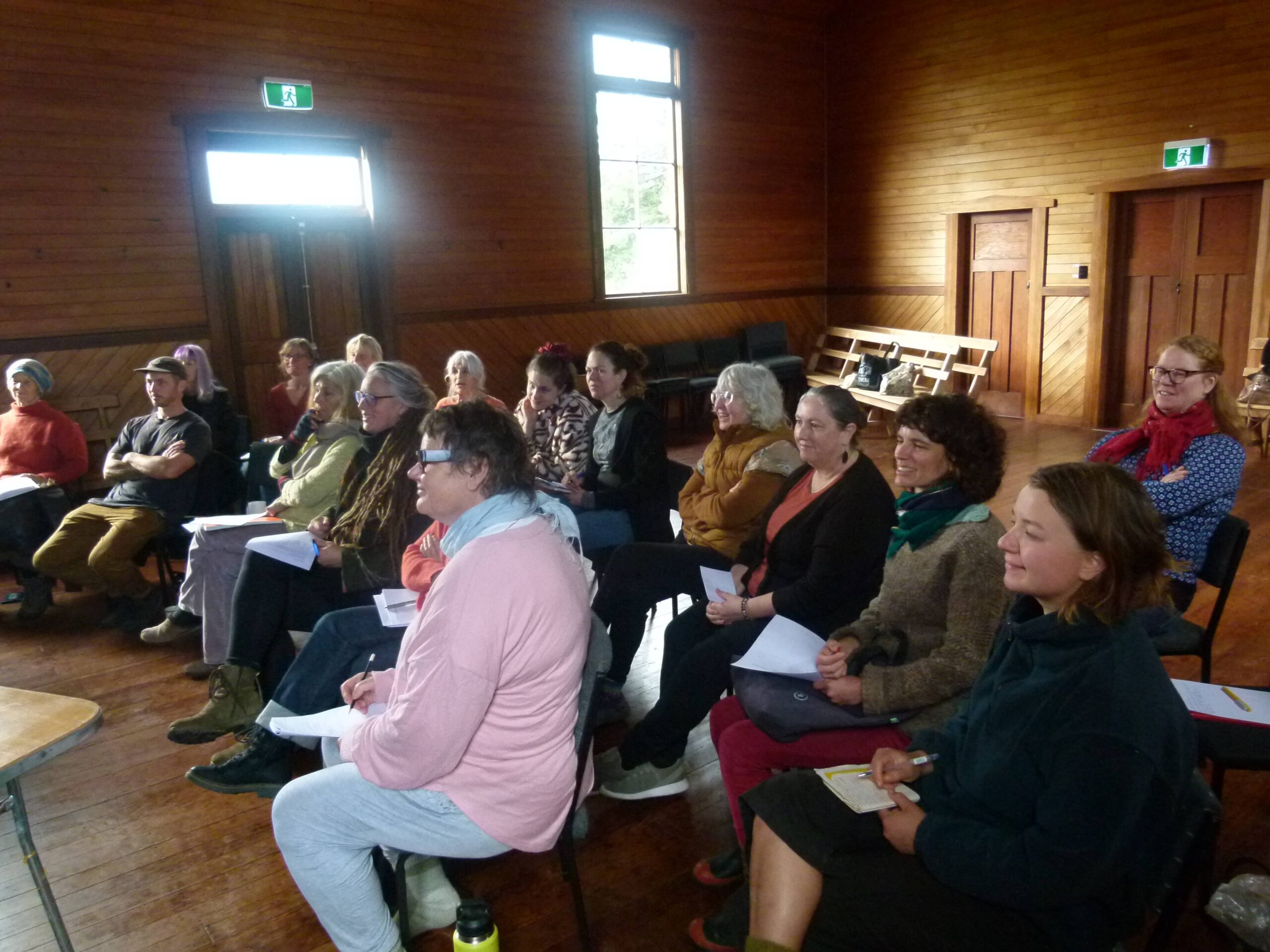 About twenty participants seated in rows at Bainham Hall, listening attentively at the Session 4 cheese making workshop of the Aorere Valley Practical Living Series