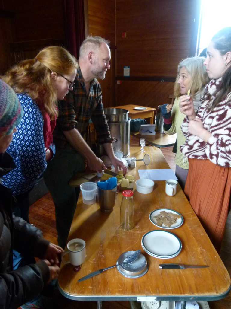 A small group of people gathered around a table at Bainham Hall, tasting and discussing five cheeses at the Session 4 Practical Living Series cheese making workshop